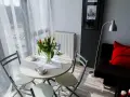 Stół z tulipanami i filiżankami, obok kanapa z czerwoną poduszką. Tak wygląda przytulna garsoniera co to.