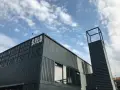 Moderne Containerarchitektur am **brlo gleisdreieck** mit Schriftzug "BALD" und einem markanten Turm unter blauem Himmel.
