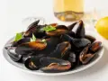 Plato de mejillones al vapor, listos para disfrutar con un toque de limón y perejil.