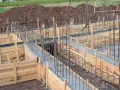Drewniany szalunek fundamentowy z zbrojeniem stalowym, gotowy do wylania betonu.