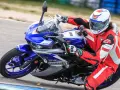 Motocyklista w czerwonym kombinezonie i kasku ściga się na torze na motocyklu Yamaha R3.