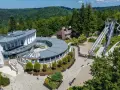 Kolej na górę parkową! Widok na kompleks z budynkami, tarasami i zjeżdżalniami w otoczeniu zielonych wzgórz.