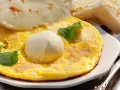 Frittata soffice con mozzarella filante, guarnita con foglie di menta fresca. Accompagnata da fette di pane tostato.