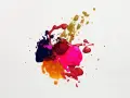 Salpicaduras de pintura vibrante en tonos morado, rosa, rojo y dorado, creando un patrón abstracto y dinámico sobre fondo blanco.