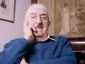 Jerzy Waldorff, znany z zamiłowania do kultury i sztuki, w niebieskim swetrze. Jego wykształcenie i pasje widoczne w tle.