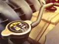 A car's radiator cap, showing warnings about hot coolant. A faulty cap can cause overheating, one of the bad radiator cap symptoms.
