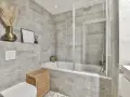 Salle de bain moderne avec carrelage gris. Une baignoire, une douche, un WC et un lavabo. Quelle colle pour carrelage salle de bain ? Une colle adaptée à l'humidité est essentielle.