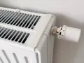 Biały grzejnik z termostatem. Dowiedz się, jak odpowietrzyć grzejnik, gdy przestaje efektywnie grzać.