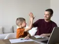Ojciec i syn dają sobie piątkę, czyli świętują sukces w nauce.