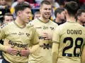 Piłkarze ręczni Górnika Zabrze w złotych strojach rozmawiają na boisku.
