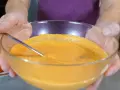 Mani che sorreggono una ciotola di vetro con una cremosa maionese di pomodoro, pronta per essere gustata.