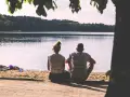 Para, siedząca na plaży, patrzy na jezioro. Idealny partner dla wagi, szukający spokoju i harmonii.