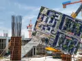 Budowa osiedla z widokiem na stare bloki, symbol patodeweloperki. Dźwigi i zbrojenia kontrastują z ułożonym na niebie zdjęciem lotniczym.