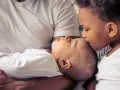 Ein älteres Kind küsst liebevoll die Stirn eines Babys. Die Frage "zweites Kind ja oder nein" scheint hier beantwortet.