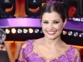 Agnieszka Sienkiewicz z kryształową kulą, uśmiechnięta na scenie w fioletowej sukience ozdobionej cekinami.