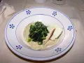 Piatto con fave e cicoria saltata, guarnito con una scaglia di formaggio e un'acciuga.