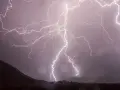 Éclairs zébrant un ciel sombre, illuminant un paysage montagneux lors d'un photo d'orage spectaculaire.