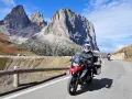 Motocyklista przemierza malowniczą drogę w Dolomitach. Pogoda dopisuje, a widoki zapierają dech w piersiach.
