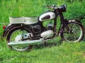 Klasyczny motocykl SHL M11 na tle zielonej trawy. Poznaj jego shl m11 dane techniczne i poczuj ducha minionej epoki.