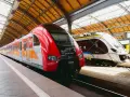 Dwa nowoczesne pociągi, czerwony i srebrny, czekają na pasażerów na dworcu. To idealny pociąg do poznania nowych miejsc.