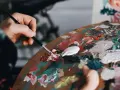 Une main mélange des couleurs vives sur une palette, prête à passer pour un peintre.