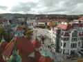 Widok na plac w Sopocie z charakterystycznymi dachami i budynkami. Wiele osób spaceruje, szukając sopotorium opinie.