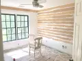 Room in progress, showing how to install shiplap on the wall. Two chairs sit on protective plastic sheeting.