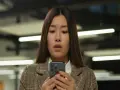 Zaskoczona kobieta patrzy na ekran telefonu komórkowego.