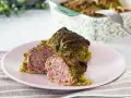 Involtini di verza con carne succulenta, uno tagliato a metà per mostrare il ripieno saporito.