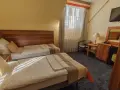 Pokój w zajazd u dziadka: dwa wygodne łóżka, stolik nocny z lampką, biurko z lustrem i krzesłem, telewizor.