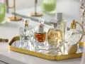 Kolekcja flakonów z płynną esencją perfum, w tym jeden z atomizerem, na złotym lustrzanym tacy.