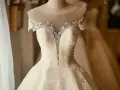 Magnifique robe de mariée, la couleur est un blanc éclatant, ornée de perles et de dentelle fine.