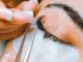 Precyzyjne przedłużanie rzęs: porównanie rzęsy 2d i 3d. Stylistka z perfekcyjnym manicurem dokłada kępki.