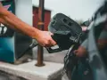 Ręka trzymająca pistolet paliwowy przy otwartym wlewie paliwa. Proces tankowania, jak spuścić paliwo z baku, jest w toku.