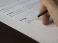 Dłoń podpisująca dokument długopisem.