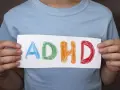 Mani di bambino tengono un foglio con la scritta "ADHD" colorata. Riconoscere i sintomi dell'ADHD è il primo passo.
