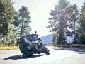 Motocyklista na zakręcie, otoczony lasem, z dumą prezentuje opony Pirelli. Jazda w stylu Pirelli klub.