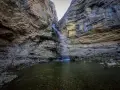 La cascada del Gollorio cae entre imponentes paredes rocosas, formando un estanque sereno.