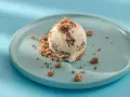 Eiscreme mit Schokoladenstückchen und Krümeln, serviert auf einem blauen Teller. Glukosesirup sorgt für die cremige Konsistenz.