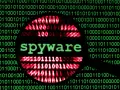 Lupa sobre código binario verde y rojo, con la palabra "spyware" en verde en el centro.