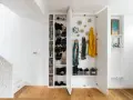 Moderne Garderobe Ideen: Offene Fächer mit Schuhen, Jacken und Schals. Ein Fahrradhelm hängt an der Wand.