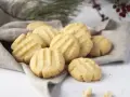 Montón de galletas de mantequilla doradas con líneas marcadas, servidas sobre una tela gris.