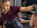 Barbero con dreadlocks y bandana camuflada corta el pelo a un cliente. ¡Reserva tus **booksy citas** para un look fresco!