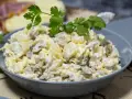Pyszna sałatka z pieczarkami, jajkiem i serem, udekorowana natką pietruszki. Idealna na każdą okazję.