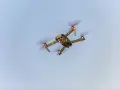 A drone flies in the sky, a reminder to check Maine drone laws before takeoff.