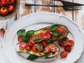 Melanzane ripiene vegetariane con pomodorini, basilico e semi di zucca, un piatto colorato e saporito.