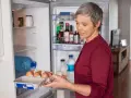 Frau holt Eier aus dem Kühlschrank. Nach einer Darmspiegelung ist leichte Kost wie Eier oft das erste Essen.