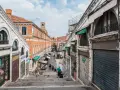 Scendendo le scale del ponte di Rialto a Venezia, si intravede un mercato vivace con negozi e bancarelle.