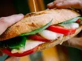 Ręce trzymają pyszne włoskie pieczywo z mozzarellą, pomidorami i bazylią. Idealne na szybki lunch.