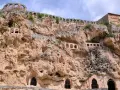 Antigua ciudad excavada en roca, con arcos y ventanas en las cuevas. Un lugar histórico que parece una cascada de piedra.